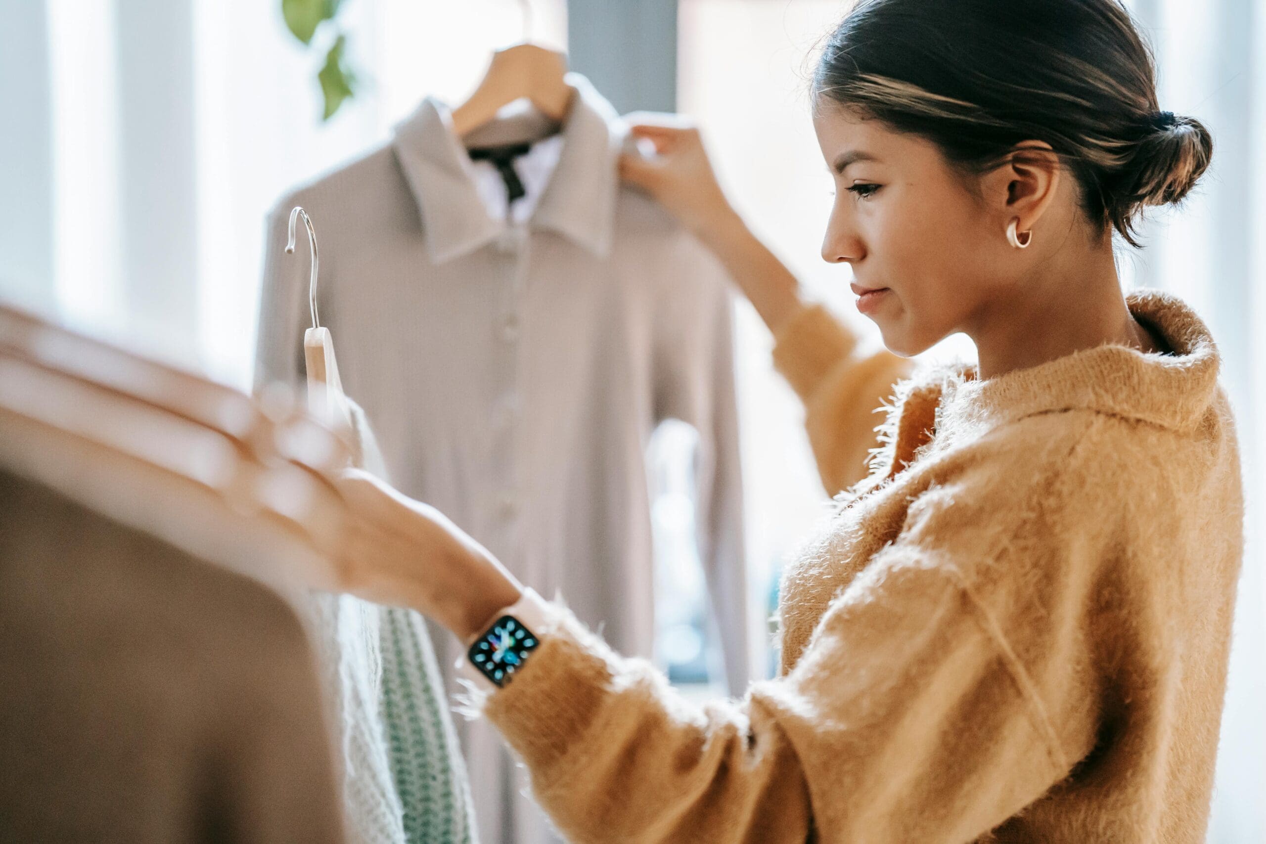 Woman deciding what to wear for a brand shoot, holding two clothing options on hangers