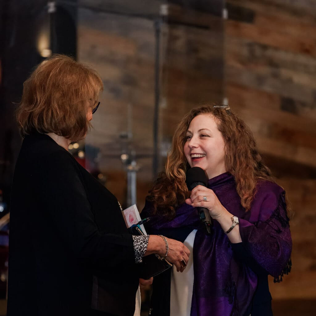 Personal brand photo showing the visual trust factor—life coach smiling and connecting authentically with speaker on stage.
